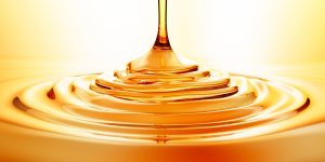 Goutte d'huile de soin naturelle tombant délicatement sur une surface douce, symbolisant le soin sur-mesure et l'approche intuitive de Pranaya Essence à Hyères.